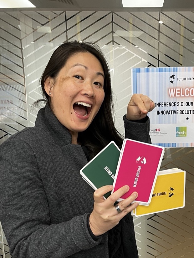 Heidi Yu Spurrell smiling, holding Future Green workshop flashcards